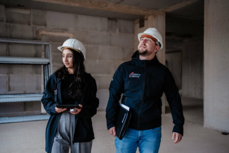 Mann und Frau mit weißem Schutzhelm auf Baustelle.