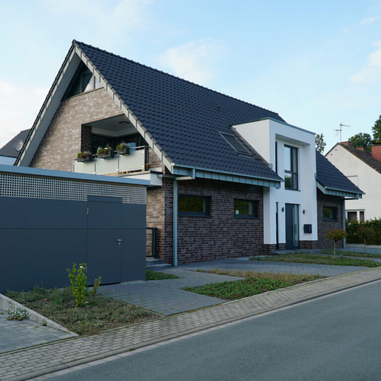 Alleinstehendes Haus mit dunklem Klinker und gepflasterter Auffahrt.