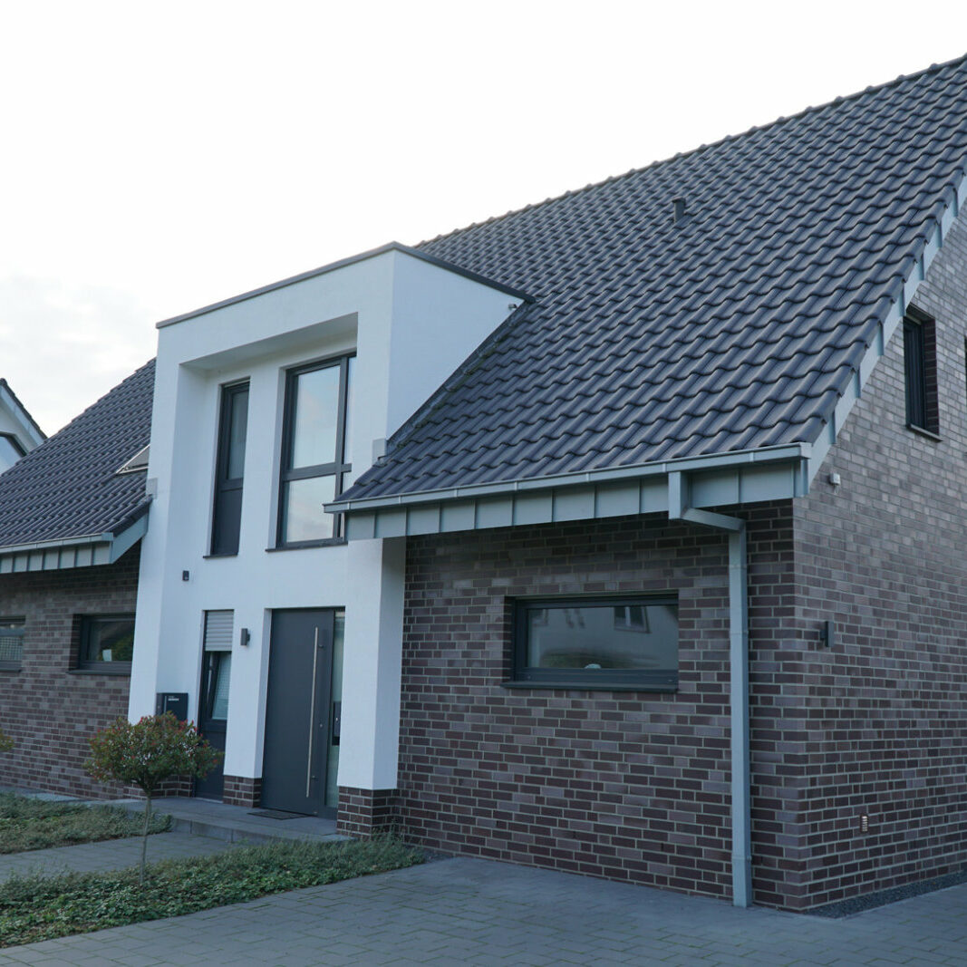 Alleinstehendes Haus mit dunklem Klinker und gepflasterter Auffahrt.