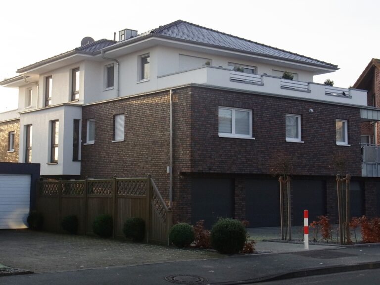 Mehrfamilienhaus mit dunklem Klinker und weißen Fenstern.