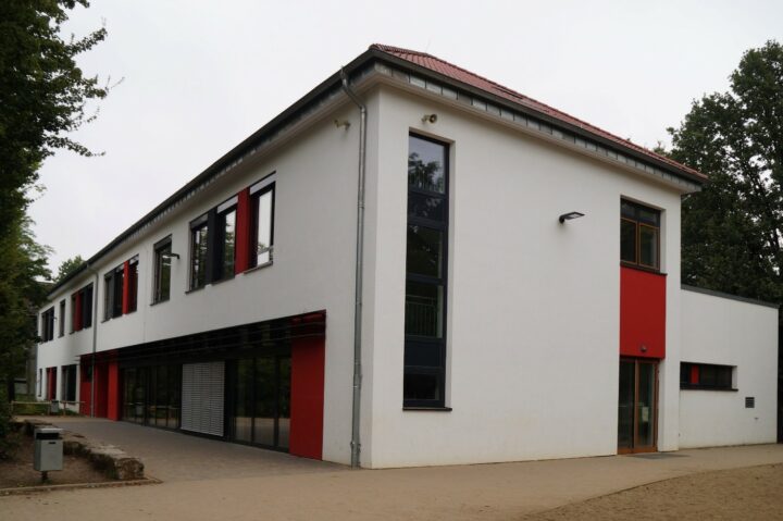 Weiß verputztes Gebäude mit roten Akzentflächen.