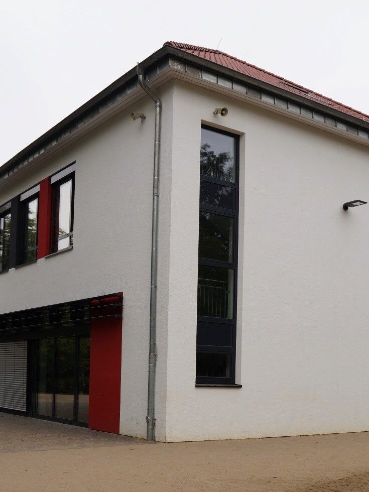 Weiß verputztes Gebäude mit roten Akzentflächen.