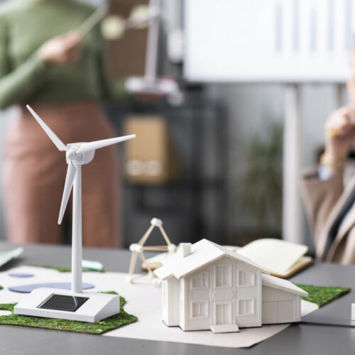 Miniaturhaus und -windanlage stehen auf Schreibtisch.