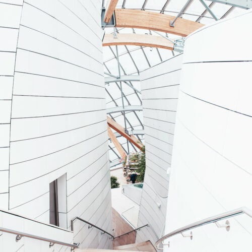 Treppenabgang mit Edelstahlgeländer umrandet von weißen Wänden.