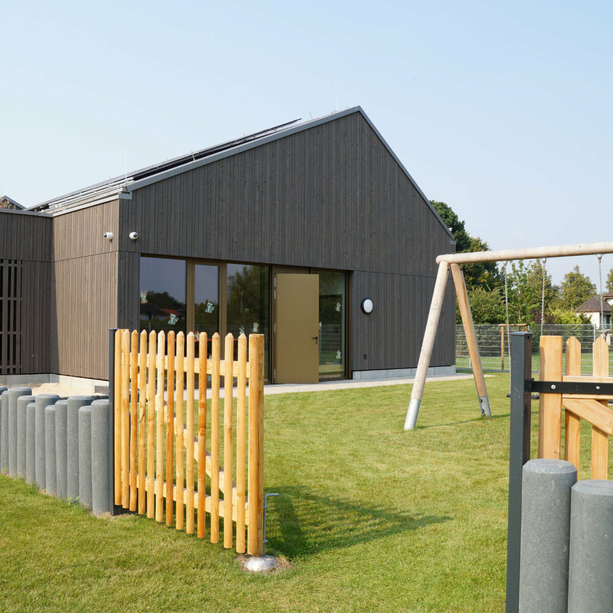 Kitagebäude mit grüner Rasenfläche und Spielplatz.