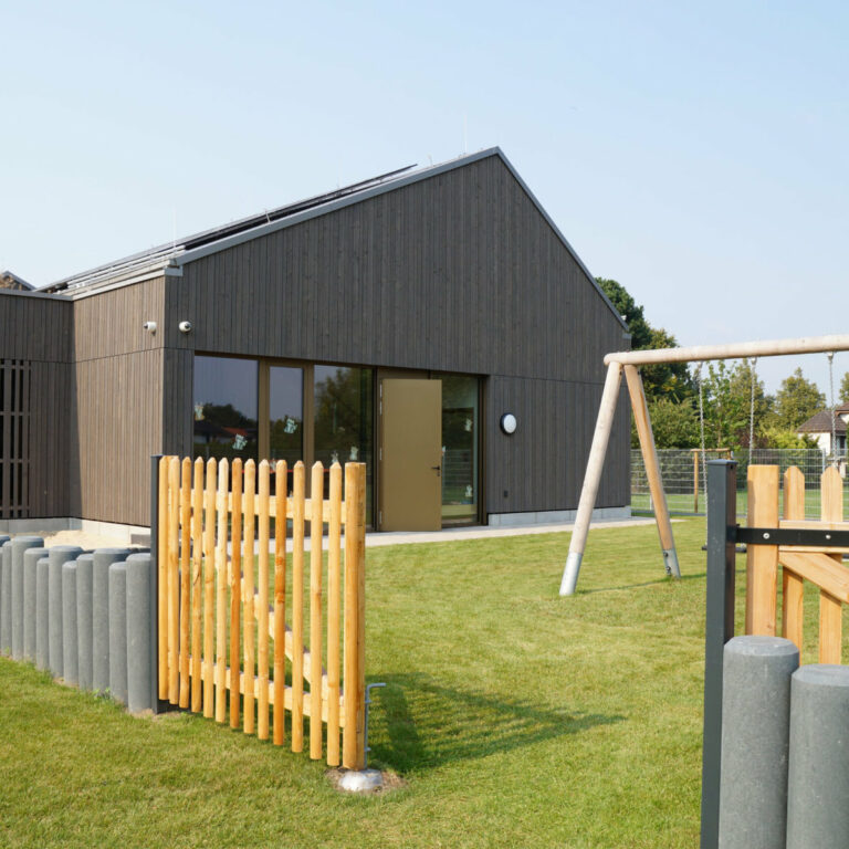 Kitagebäude mit grüner Rasenfläche und Spielplatz.