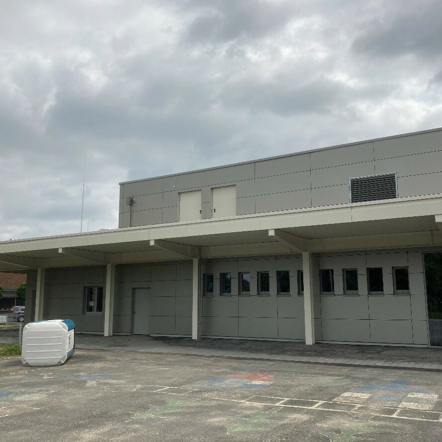 Graues Gebäude mit kleinen Fenstern und langem Abdach.