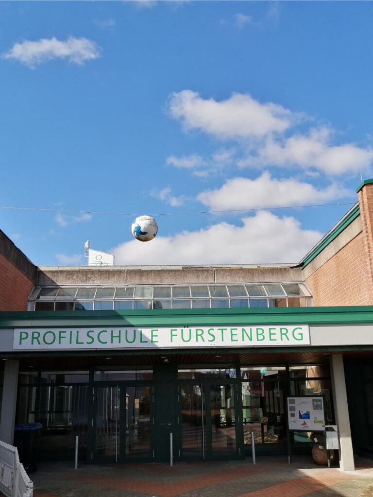 Rotes Backsteingebäude mit grünen Fenstern und der Aufschrift Profilschule Fürstenberg.