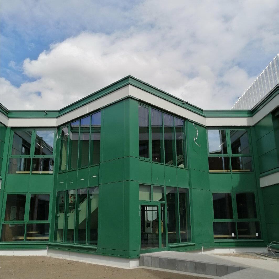 Grau gepflasterter Weg vor grüner Fensterfront.